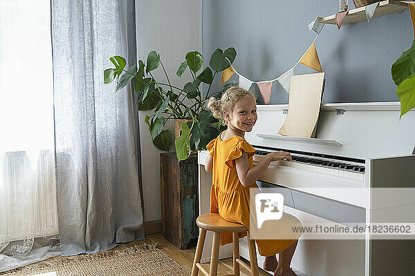 Smiling girl practicing piano at home