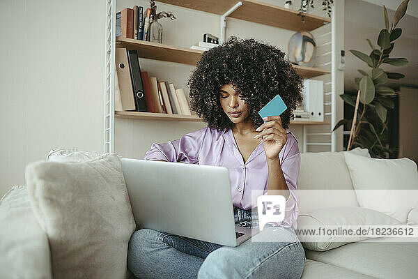 Junge Frau mit Kreditkarte beim Online-Shopping am Laptop zu Hause