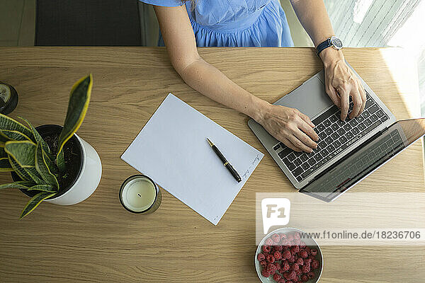 Hands of businesswoman using laptop at desk in home office