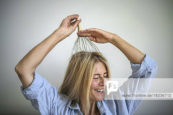 Happy woman enjoying scalp massage through massager at home