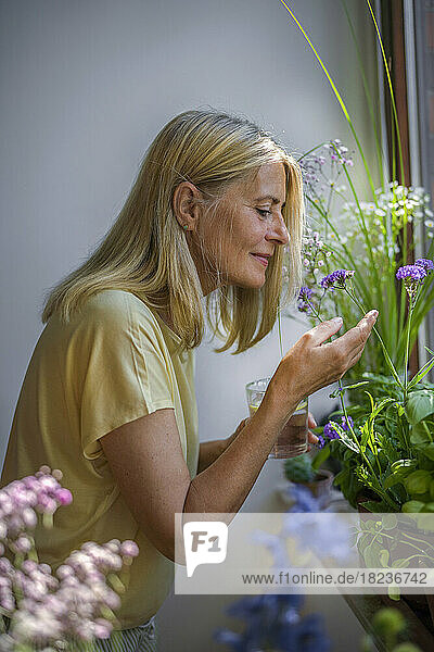 Mature man smelling flower near window at home