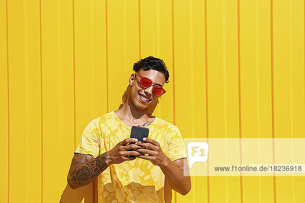 Lächelnder junger Mann  der ein Selfie vor einer gelben Wand macht