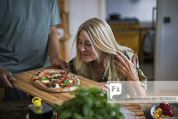 Mature woman with blond hair looking at pizza