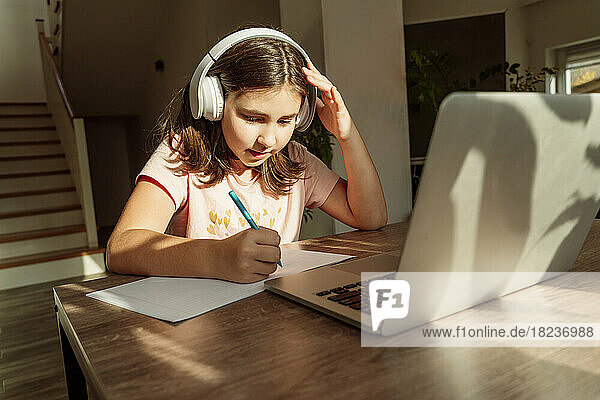 Mädchen mit kabellosen Kopfhörern lernt zu Hause