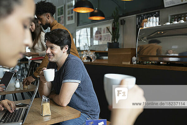 Lächelnder Mann  der Kaffee im Café trinkt