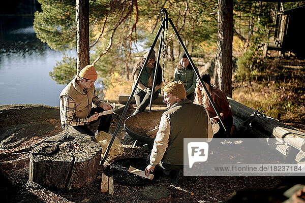 Gemischtrassige Freunde verbringen ihre Freizeit an der Feuerstelle beim Camping