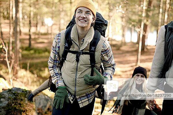 Happy man looking away while hiking with friends in forest