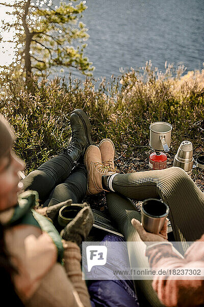High angle view of friends wearing boots while sitting on grass during camping