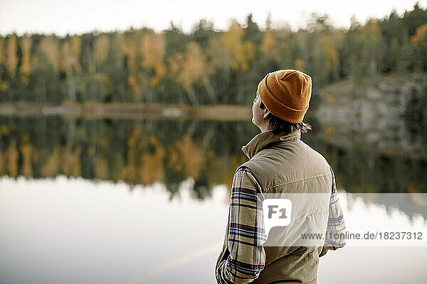 Rear view of young man with hand in pocket spending time near lake