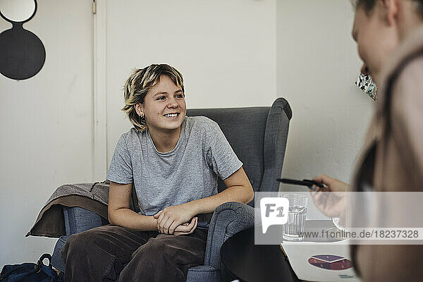 Smiling female student listening to counselor discussing in school office