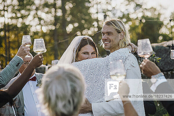 Lächelndes frisch vermähltes Paar tanzt inmitten von Familie und Freunden bei der Hochzeit
