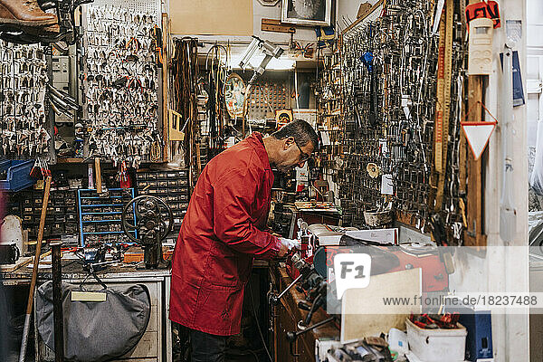 Side view of male locksmith working in repair shop