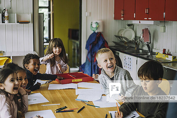 Cheerful male and female students enjoying while learning in kindergarten