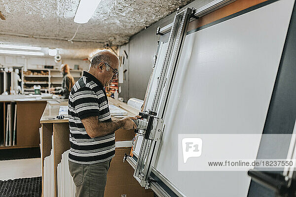 Seitenansicht eines Handwerkers beim Siebdrucken in der Werkstatt