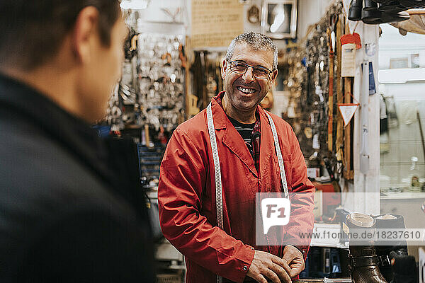 Happy locksmith talking with male customer in workshop