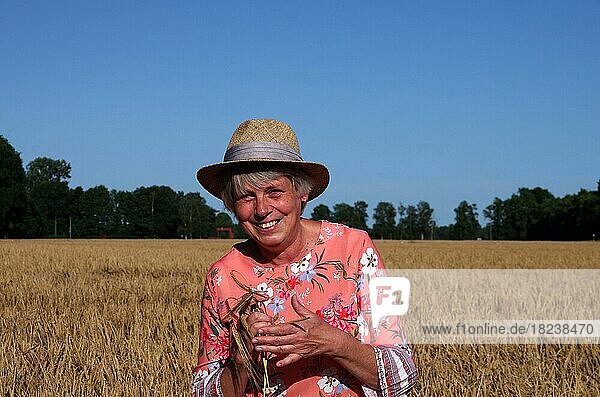 Porträt  Frau  weiblich  draußen  eine Frau mit Strohhut steht in einem Getreidefeld