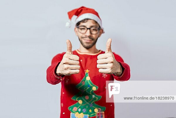 Young man in christmas hat giving thumbs up with both hands. People in santa hat ok gesture with fingers isolated. Christmas man concept with thumbs up in ok gesture