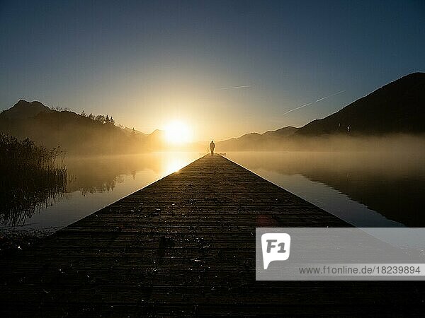 Morgenstimmung bei Sonnenaufgang  Person im Gegenlicht auf Steg am Fuschlsee  Fuschl am See  Salzkammergut  Oberösterreich