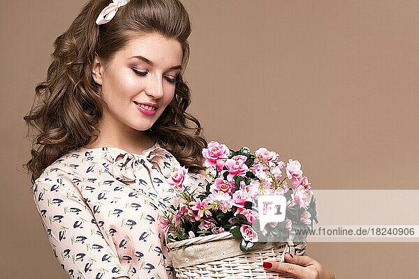 Frisches junges Mädchen in einem leichten Seidenkleid  Lächeln  Retro-Locken im Pin-up-Stil mit einem Blumenkorb in den Händen. Schönes Gesicht und Körper. Fotos im Studio aufgenommen