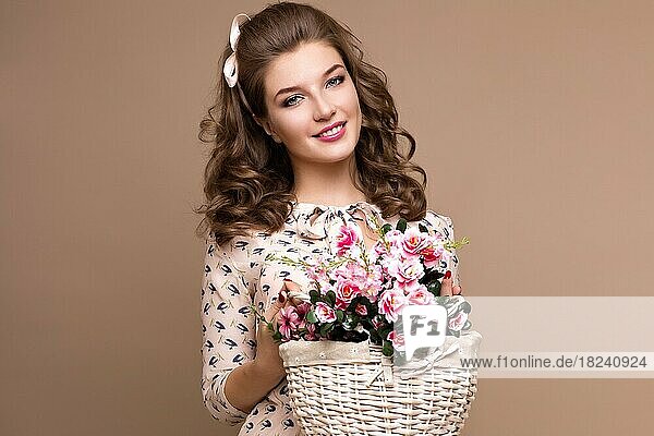 Fresh young girl in a light silk dress  smile  retro curls in the style of pin-up with a basket of flowers in her hands. Beauty face and body. Photos shot in studio