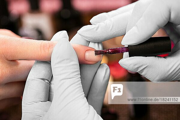 Closeup Fingernagelpflege von Maniküre-Spezialist in Schönheitssalon. Maniküre malt Nägel mit rotem Nagellack