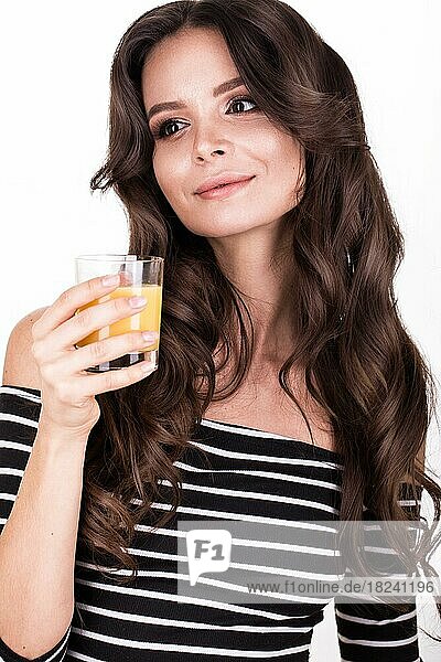 Schöne Frau mit gesunder Haut  lockigem Haar und Orangensaft posiert im Studio. Schönheit Gesicht