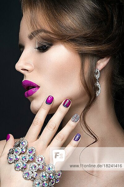 Beautiful girl with a bright evening make-up and purple manicure with rhinestones. Nail design. Beauty face. Picture taken in the studio on a black background