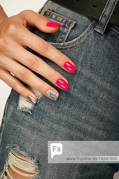 Bright neon manicure on female hands on the background of jeans. Nail design. Beauty hands