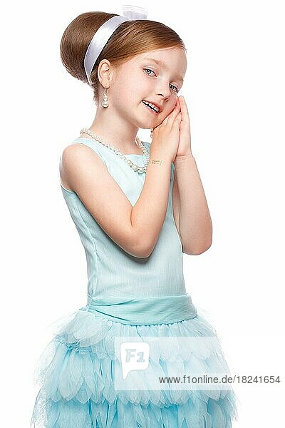 Ein kleines Mädchen in einem blauen Kleid  mit einer Retro-Frisur und Accessoires. Foto im Studio aufgenommen