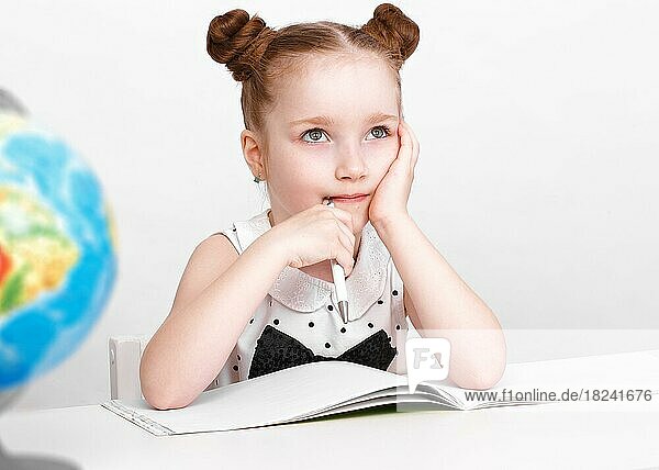 Kleines Mädchen am Tisch einer Erstklässlerin. Foto im Atelier aufgenommen