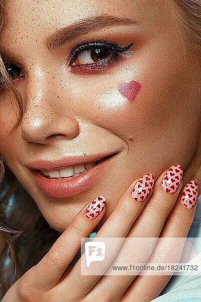 Hübsches Mädchen mit Lockenfrisur  klassischem Make-up  Sommersprossen  nackten Lippen und Maniküre-Design. Schönheit Gesicht. Das Bild für Valentinstag  Kunst Nägel. Studio Porträt