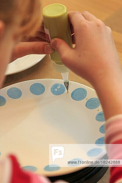 Ein Kind bemalt und verziert künstlerisch einen Teller