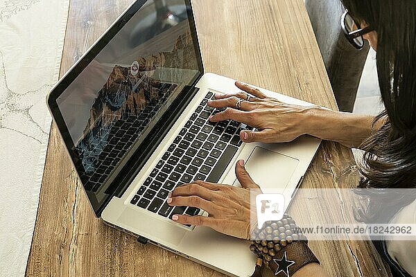 High angle view of the hands of a woman typing on a laptop keyboard