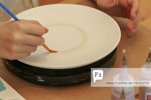Ein Kind bemalt und verziert einen Teller