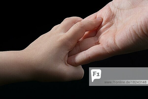 Erwachsener und Kind halten Hände in schwarzem Hintergrund