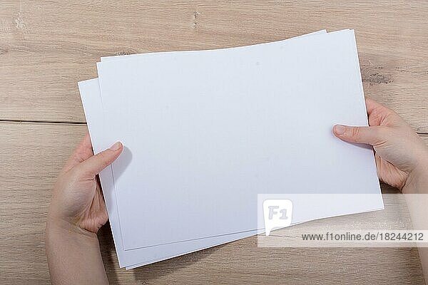 Eine Hand hält ein Blatt Papier auf einem hölzernen Hintergrund
