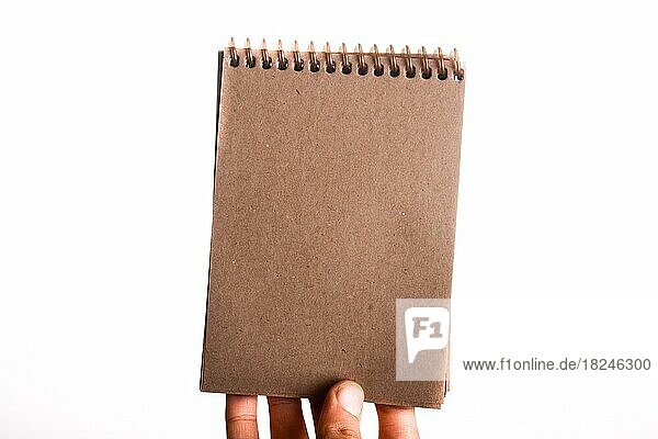 Spiralförmige braune Notizbuch in Kind Hand auf einem weißen Hintergrund