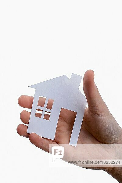 Hand hält ein isoliertes Papierhaus mit weißem Hintergrund