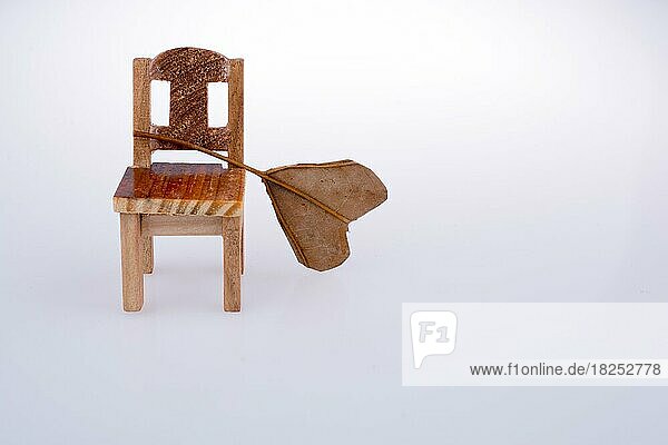 Herzform geschnitten trockenes Blatt auf einem kleinen Modell Stuhl auf einem weißen Hintergrund setzen