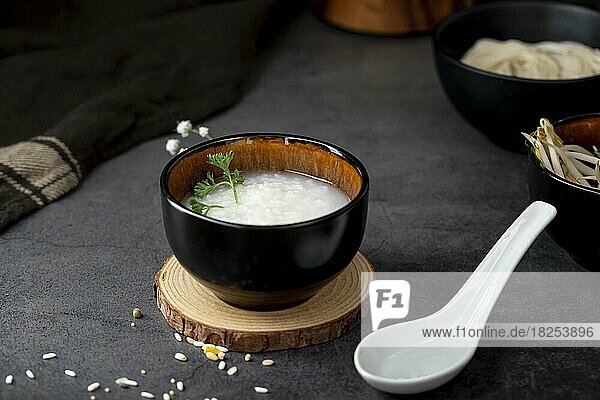 Reissuppe schwarze Schüssel hölzerne Unterstützung weißer Löffel  Auflösung und hohe Qualität schönes Foto