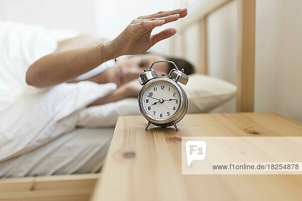 Frau schaltet den Wecker aus  während sie im Bett liegt. Auflösung und hohe Qualität schönes Foto