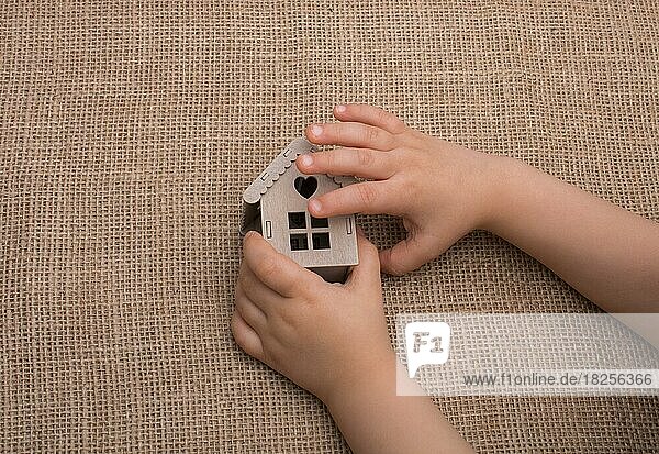 Kind hält ein Modellhaus auf einer Leinenleinwand