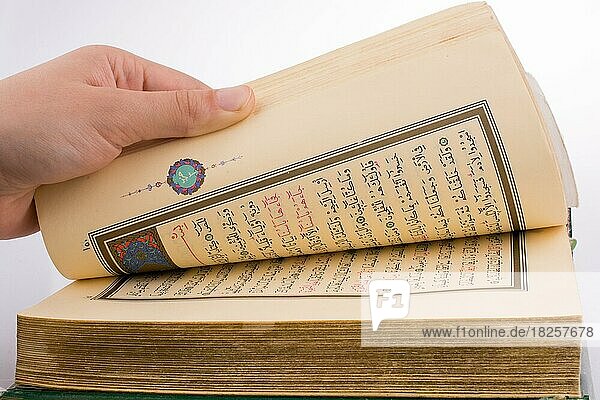 Hand hält den Heiligen Koran auf weißem Hintergrund