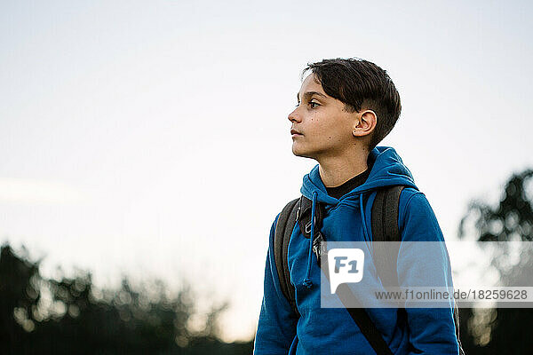 Profile Of Boy Outside In Blue Hoodie And Backpack