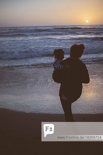 Mother holding child on a beach at night in California