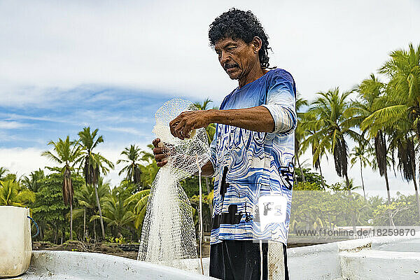 Fisherman preparing his net on the shore.