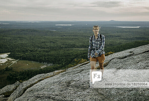 Young woman in plaid shirt and backpack hikes Schoodic Mountain  Maine