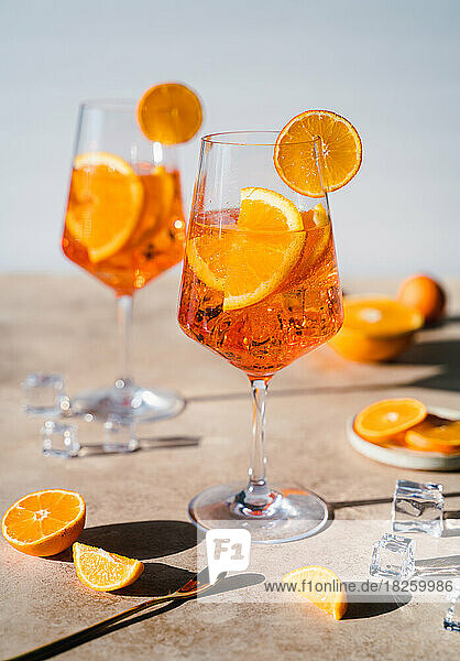 Close up of two aperol spritz drinks on sunny beige background.