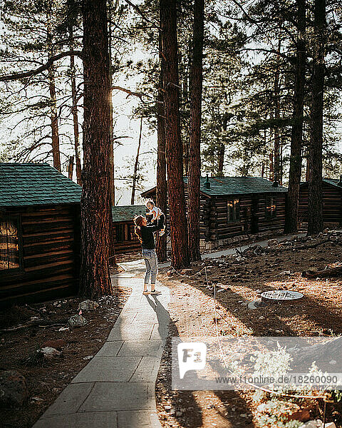 Mother and daughter walking on a sidewalk through cabins in a fo