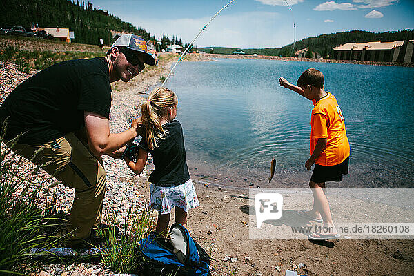 Family catches fish on vacation lakeside in the mountains